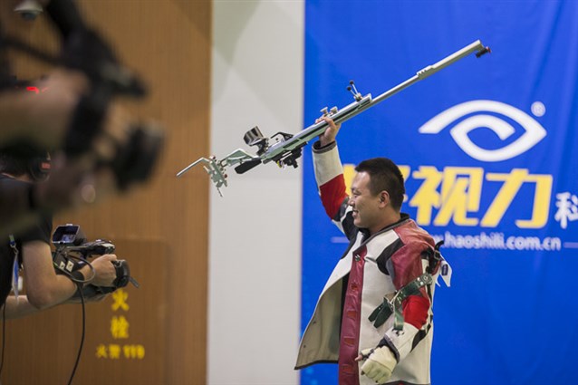 Two Chinese flags weave upon the 50m Rifle Prone Men podium